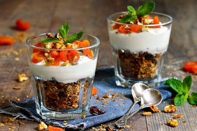Dessert from granola,yogurt,nuts and dried apricot in a glass.